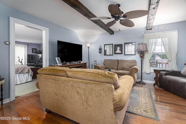 living room featuring plenty of natural light, a ceiling fan, wood finished floors, and beam ceiling