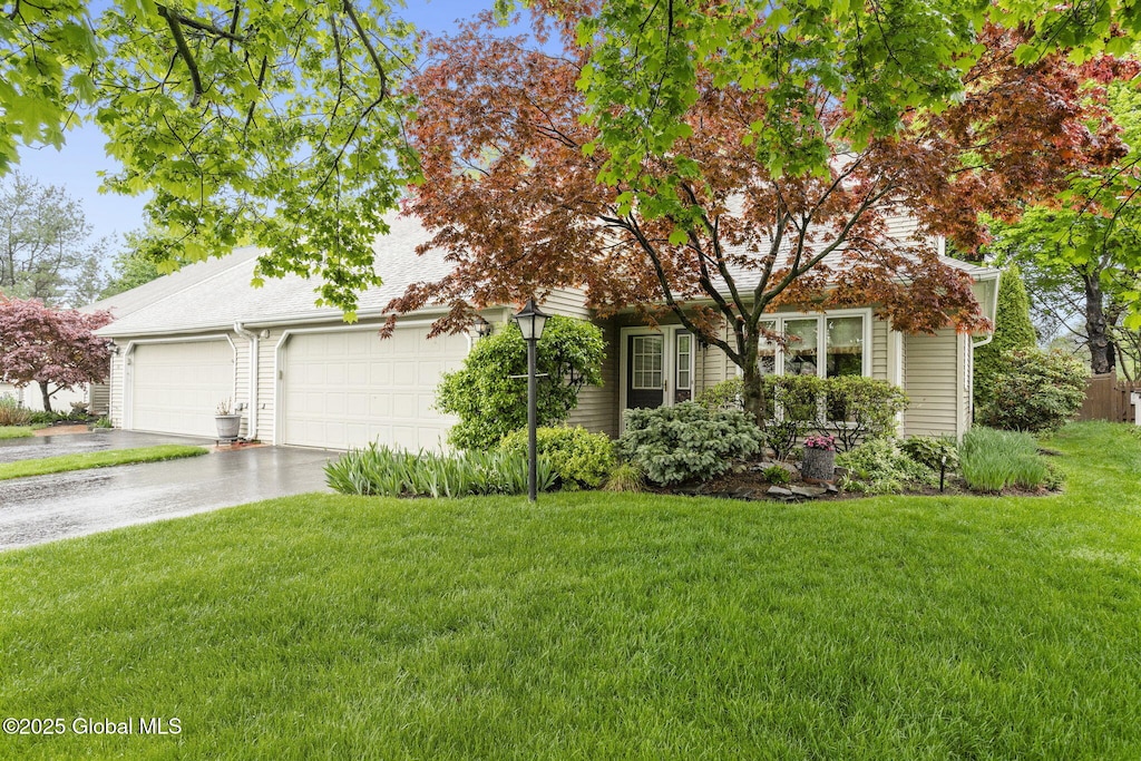 obstructed view of property featuring concrete driveway, a front yard, and a garage