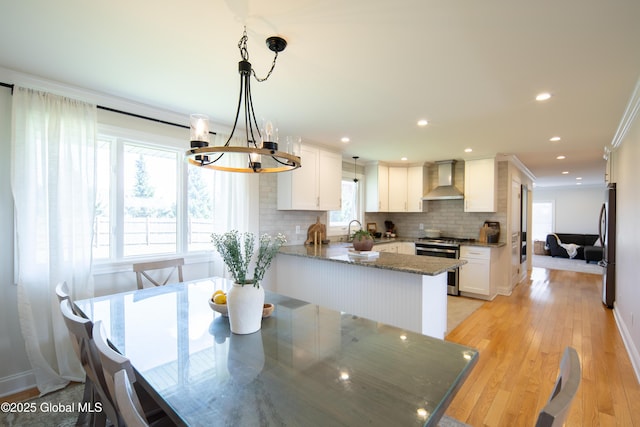 dining area featuring recessed lighting, light wood-style flooring, crown molding, and a notable chandelier