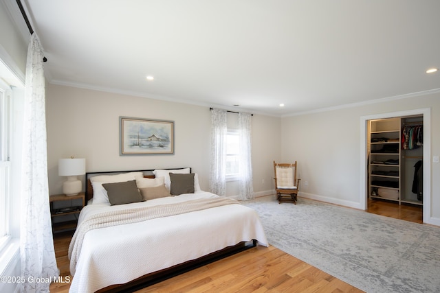 bedroom with recessed lighting, wood finished floors, a spacious closet, and crown molding