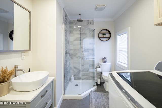 bathroom with a shower stall, visible vents, toilet, ornamental molding, and washer / clothes dryer