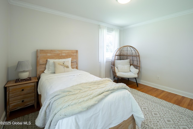 bedroom featuring baseboards, wood finished floors, and crown molding