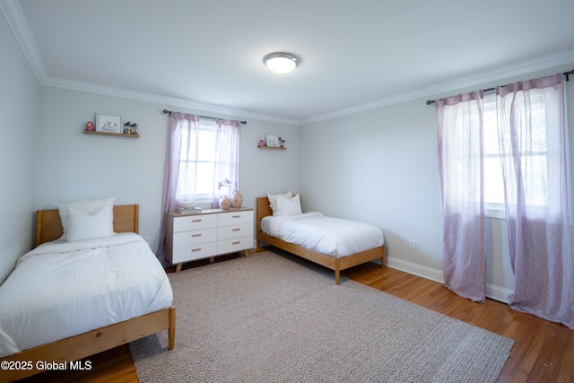 bedroom featuring baseboards, wood finished floors, and crown molding