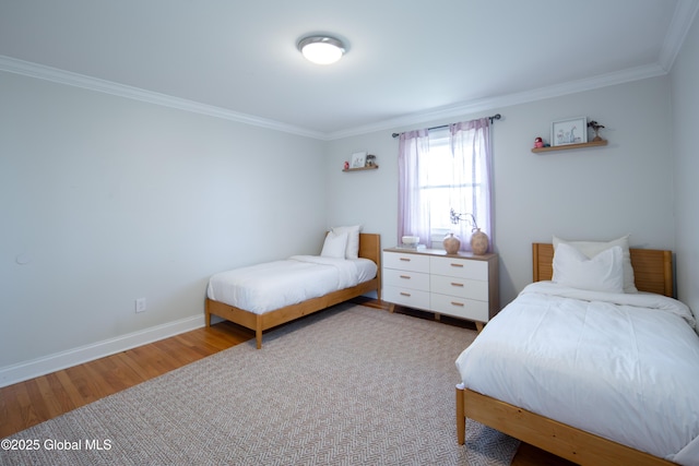 bedroom featuring baseboards, wood finished floors, and crown molding