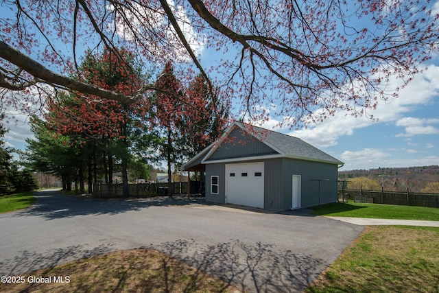 detached garage featuring fence and aphalt driveway