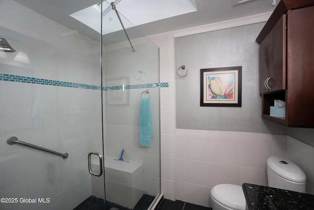 full bathroom featuring a stall shower, toilet, and tile walls