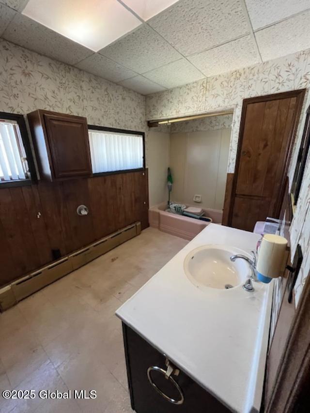 bathroom with a baseboard heating unit, wallpapered walls, and a paneled ceiling