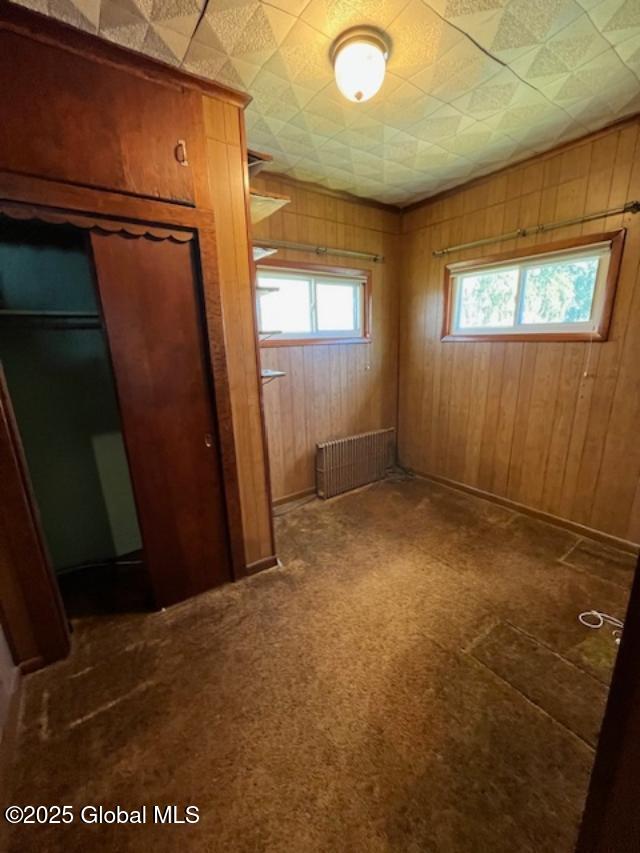 spare room featuring wood walls and radiator heating unit