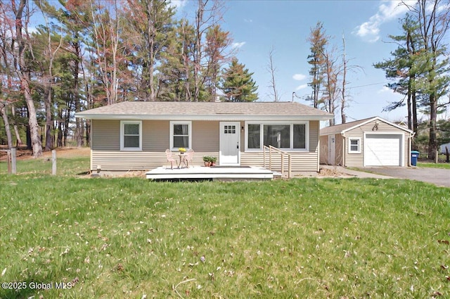 ranch-style house featuring a detached garage, driveway, an outbuilding, a front yard, and a wooden deck