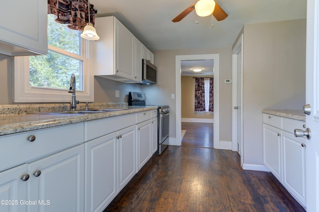 kitchen featuring white cabinets, stainless steel appliances, a sink, a ceiling fan, and dark wood-type flooring