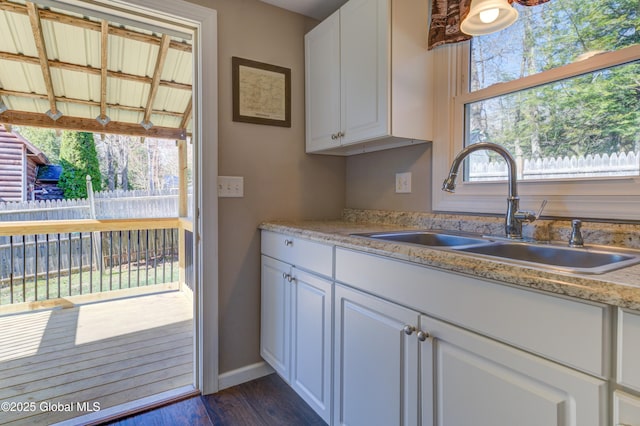kitchen featuring baseboards, a sink, white cabinetry, and dark wood-style flooring