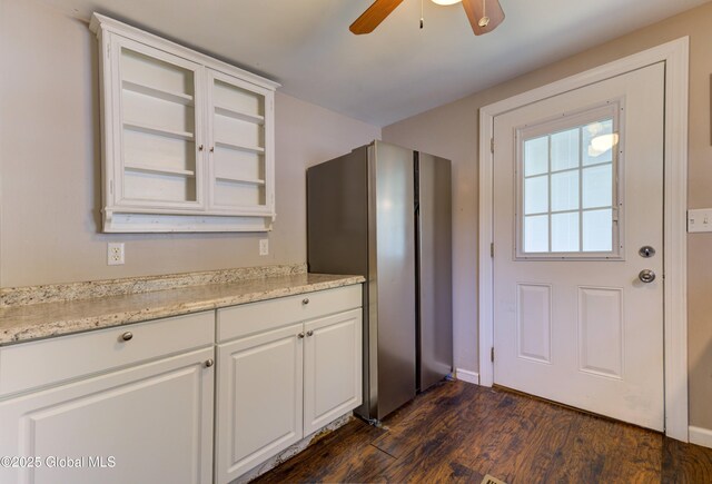 kitchen featuring white cabinets, glass insert cabinets, ceiling fan, dark wood finished floors, and baseboards