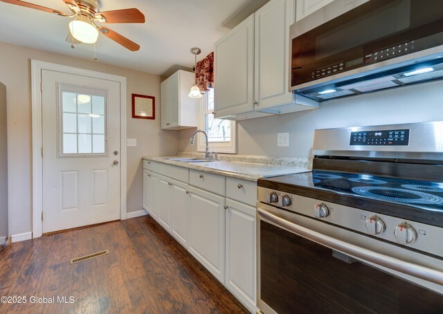 kitchen with a sink, stainless steel appliances, light countertops, dark wood finished floors, and white cabinetry