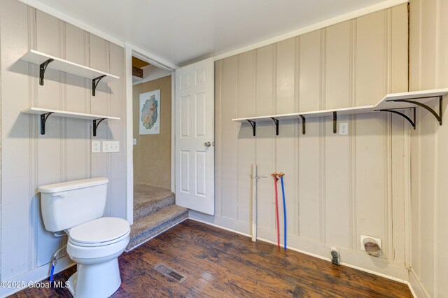 bathroom featuring a decorative wall, toilet, wood finished floors, and visible vents