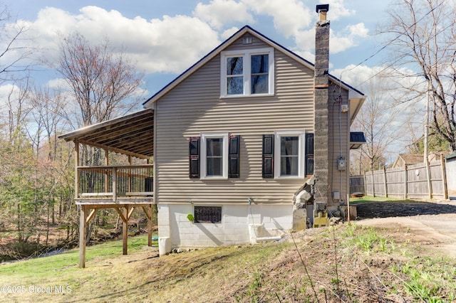 rear view of property featuring a chimney, fence, and a deck