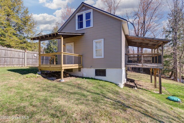 rear view of property with fence, a wooden deck, and a yard