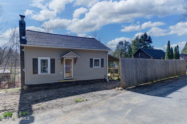 bungalow-style home featuring a chimney and fence