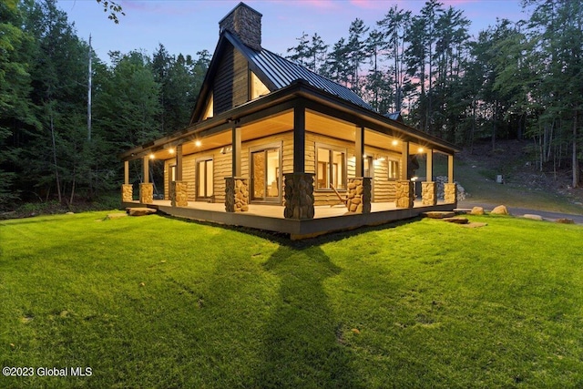 1181 Hunt Lake Rd Unit N, Corinth, NY 12822 - back of property at dusk with a chimney, a standing seam roof, a yard, and covered porch