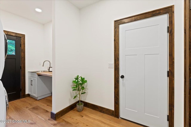 1181 Hunt Lake Rd Unit N, Corinth, NY 12822 - laundry area with light wood finished floors, a sink, baseboards, stacked washer and clothes dryer, and cabinet space