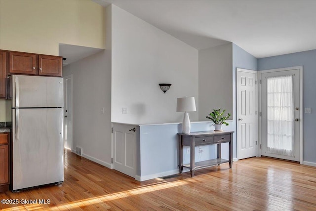 kitchen with freestanding refrigerator, baseboards, visible vents, and light wood-style floors