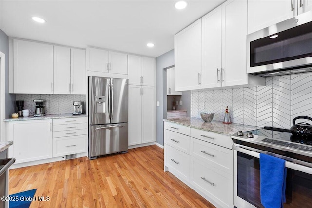 kitchen with appliances with stainless steel finishes, backsplash, white cabinetry, and recessed lighting
