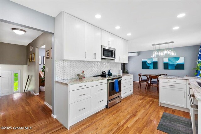 kitchen featuring appliances with stainless steel finishes, decorative backsplash, white cabinetry, light wood-style floors, and recessed lighting