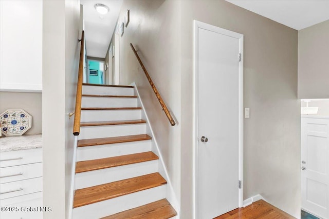 staircase featuring wood finished floors and baseboards