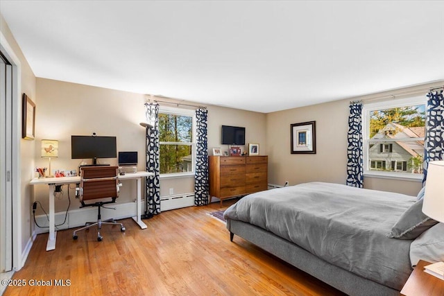 bedroom with wood finished floors, an office area, and baseboard heating
