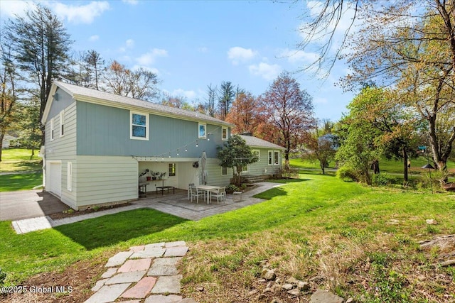 back of property featuring an attached garage, a patio, a yard, and driveway