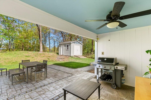 view of patio with outdoor dining area, a shed, an outdoor structure, ceiling fan, and a grill