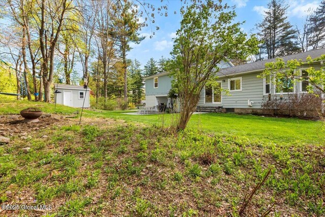 view of green lawn featuring a storage shed, an outbuilding, and entry steps