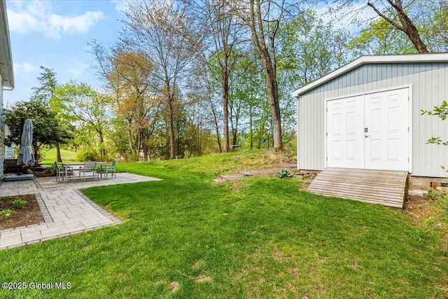 view of grassy yard with a patio area and an outbuilding