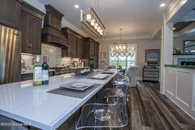 kitchen with dark brown cabinets, light stone countertops, backsplash, and dark wood finished floors