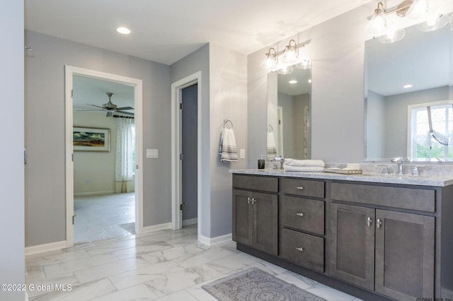full bathroom with a sink, double vanity, baseboards, ceiling fan with notable chandelier, and marble finish floor