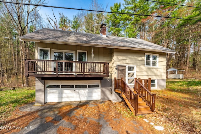 view of front of home with a chimney, roof with shingles, driveway, and an attached garage
