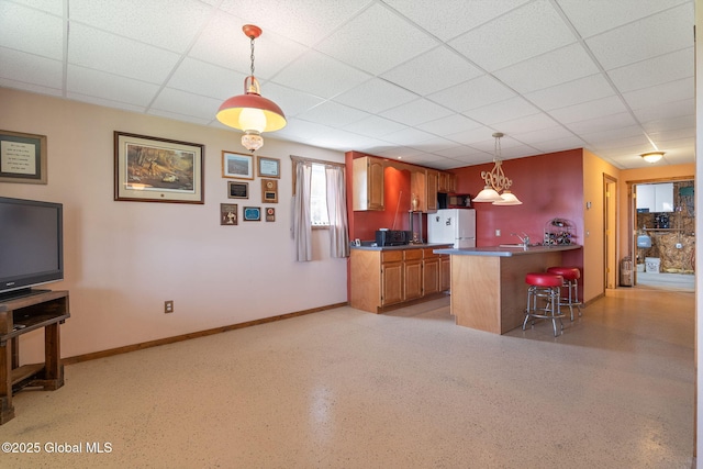 2694 State Route 10, Summit, NY 12175 - kitchen featuring freestanding refrigerator, a peninsula, brown cabinets, a kitchen breakfast bar, and hanging light fixtures