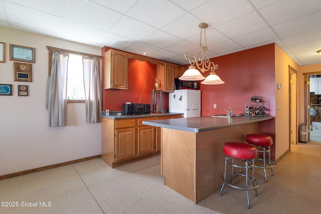 2694 State Route 10, Summit, NY 12175 - kitchen with freestanding refrigerator, a sink, a kitchen bar, a peninsula, and a paneled ceiling