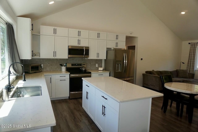 kitchen with white cabinets, dark wood finished floors, stainless steel appliances, backsplash, and a sink