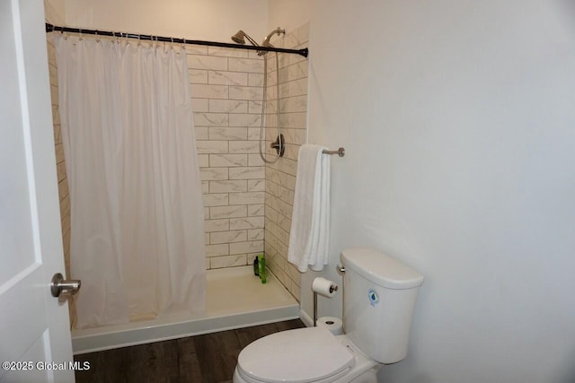 bathroom featuring toilet, wood finished floors, and tiled shower