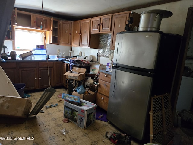 kitchen with freestanding refrigerator, open shelves, decorative backsplash, brown cabinets, and light floors