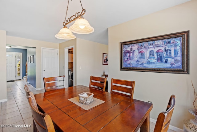 dining room with baseboards, washer / dryer, and light tile patterned floors