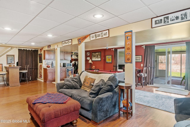 living room with recessed lighting, a drop ceiling, and wood finished floors