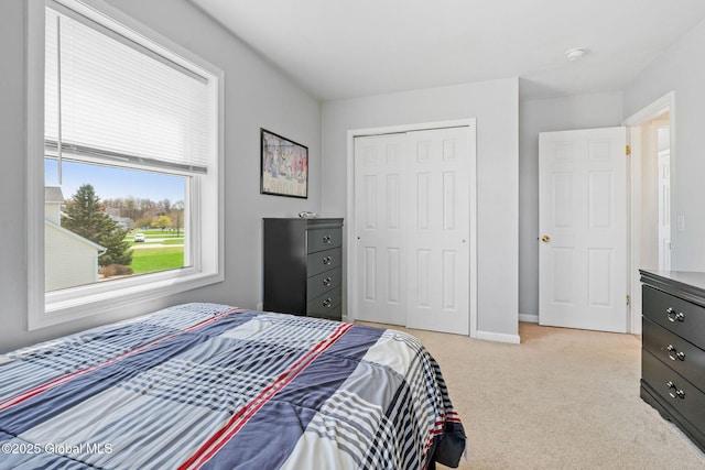 bedroom with baseboards, light carpet, and a closet