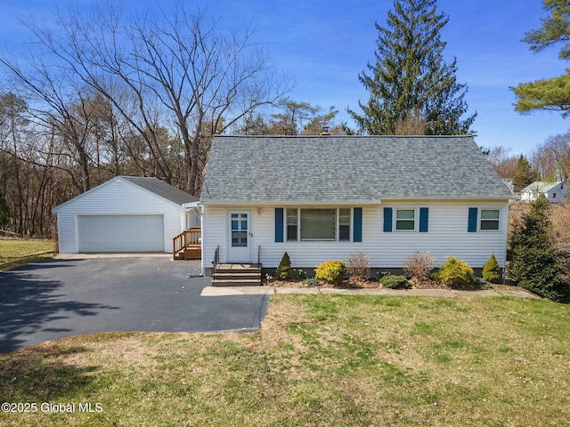 view of front of property featuring a shingled roof, an outbuilding, a front yard, and a detached garage