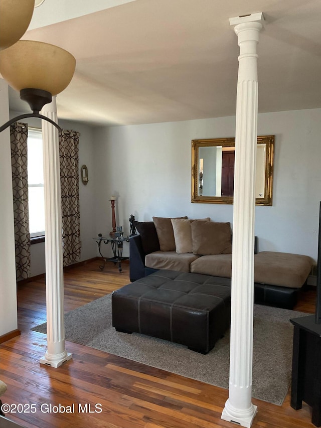 living area with wood finished floors and decorative columns
