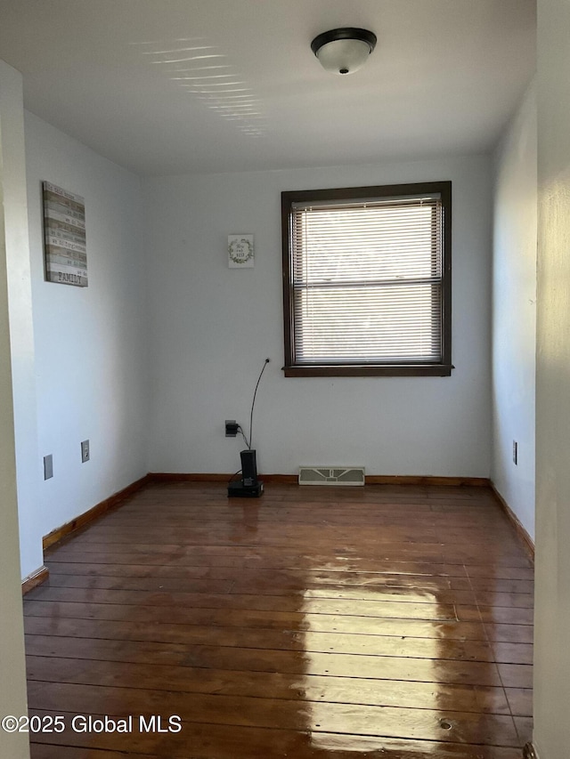 spare room with visible vents, baseboards, and wood-type flooring