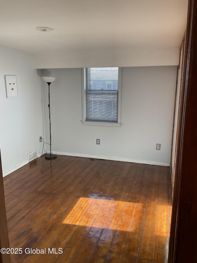 spare room with visible vents, hardwood / wood-style floors, and baseboards