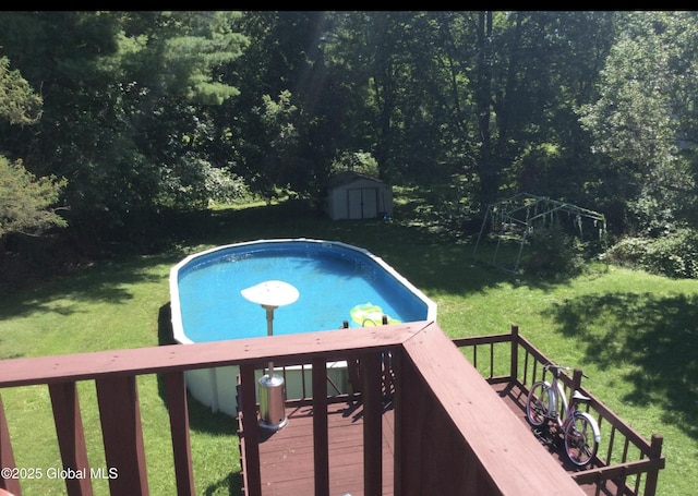 view of pool with a deck, an outbuilding, a yard, and a storage shed