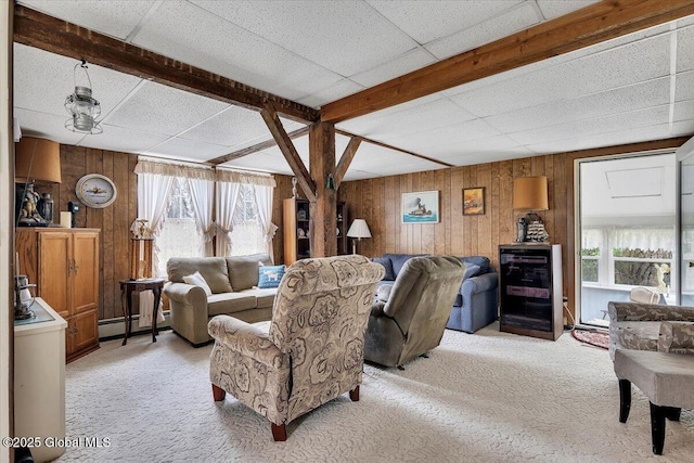 living area featuring a paneled ceiling, wooden walls, light carpet, and baseboard heating