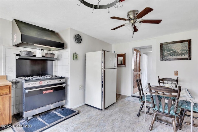 kitchen with exhaust hood, stainless steel gas range, ceiling fan, freestanding refrigerator, and light wood-type flooring
